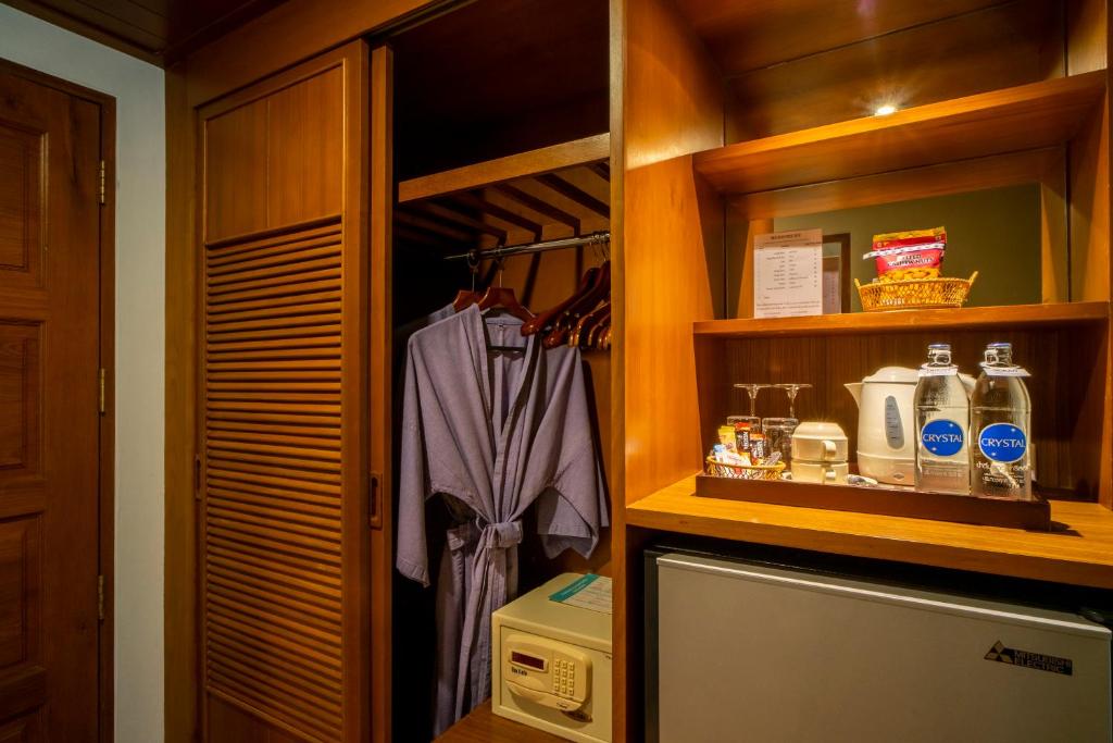 Koka skapīša iekšpuse ar halātu, pakaramiem un mini bāru, kurā ir ūdens, tēja un uzkodas.