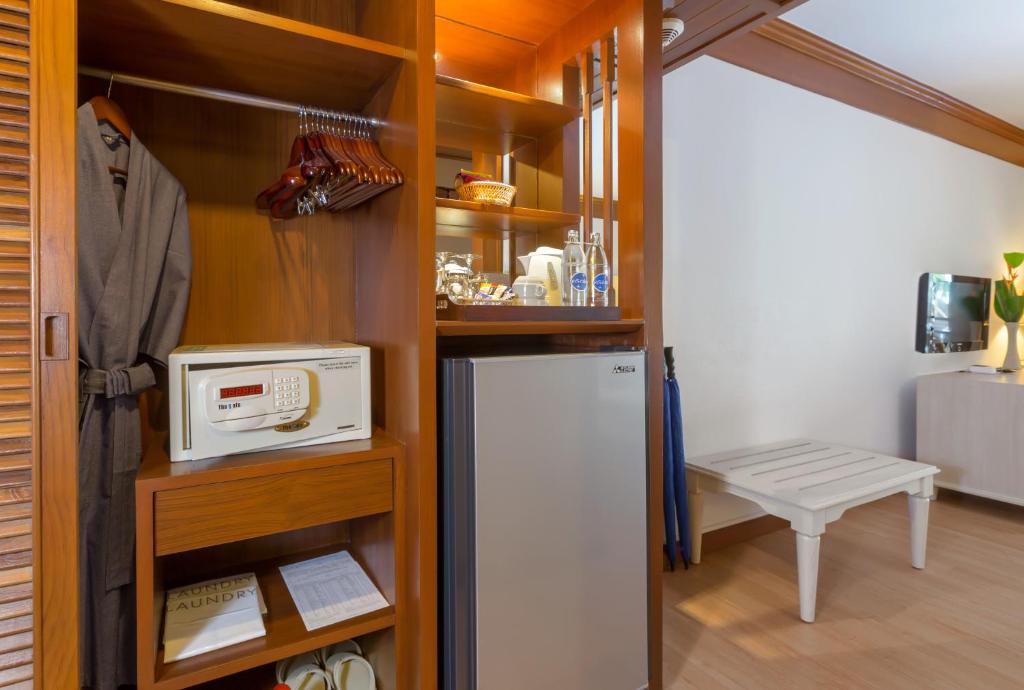 Mūsdienīga viesnīcas istabas niša ar drēbju skapja, seifa un mini ledusskapja elementiem, kā arī ērtu apģērbu un aksesuāru uzglabāšanai.