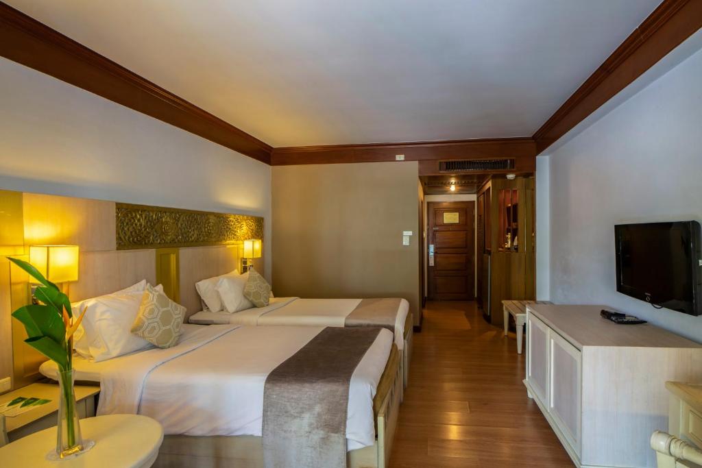 Mūsdienīga viesnīcas numura iekārtojums ar divām atsevišķām gultām, gaismas avotiem un televizoru. Telpā ir koka grīda un dekoratīvi elementi, kas rada komfortablu atmosfēru.