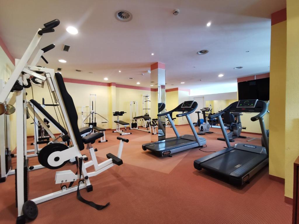 Mūsdienīgs sporta zāles iekārtojums ar dažādām trenažieriem, tostarp skrejceliņiem un svaru trenažieriem. Telpa ir gaiša un plaša, radot iedvesmojošu vidi fiziskajām aktivitātēm.