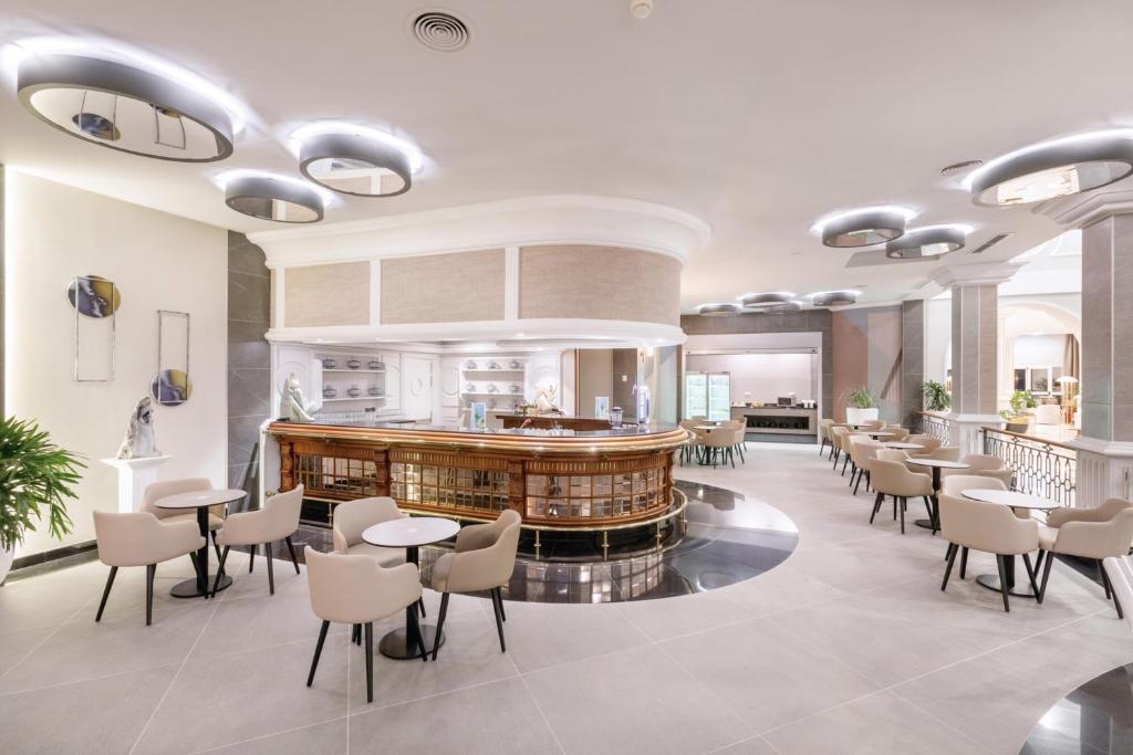 Mūsdienīgs bārs ar elegantu dizainu, kurā ir stilīgas krēsli un apaļi galdi. Interjerā redzami moderni apgaismojumi un dekoratīvi elementi, radot patīkamu atmosfēru.