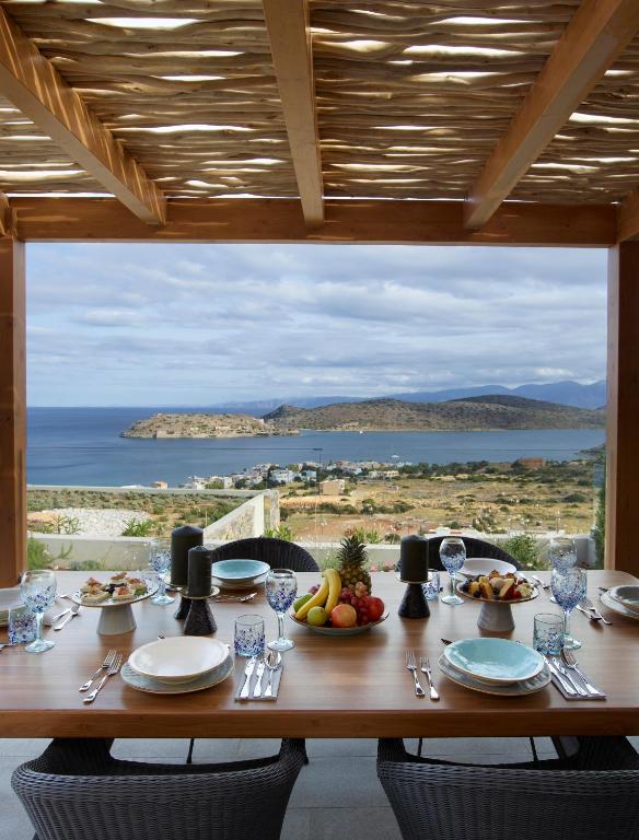 Elegantā terase ar skatu uz jūru, izvietota ar gaumīgu galdu, kas klāts ar augļiem un traukiem. Ideāla vieta relaksācijai un maltītēm brīvā dabā.