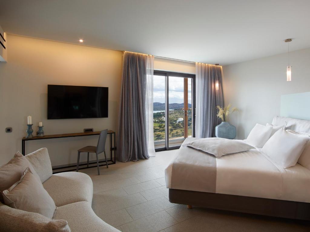 Mūsdienīgs viesnīcas numurs ar plašu logu, kas piedāvā skatu uz ainavu. Interjerā ir ērtas mēbeles, televizors un gaiši toņi, radot relaksējošu atmosfēru.