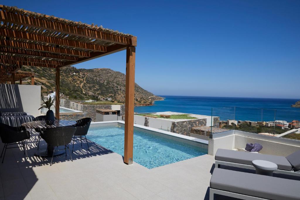 Mūsdienīga terase ar baseinu un skatu uz jūru, apņemta ar kalnu ainavām. Ideāla vieta atpūtai un relaksācijai saulainā dienā.