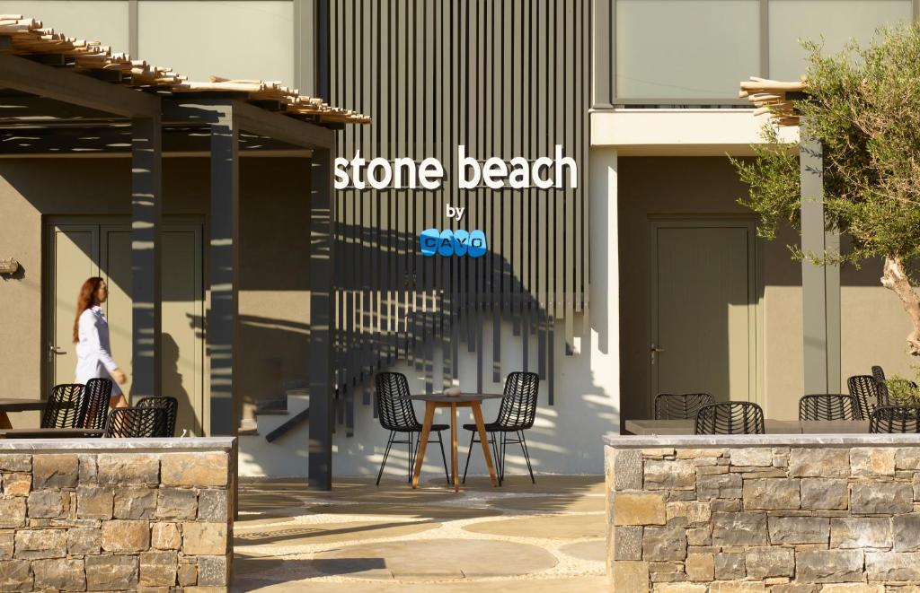 Mūsdienīgs āra kafijas laukums ar zīmolu "stone beach by CAYO", kurā redzamas melnas krēsli un galdi. Apspīdēts ar sauli, šis dizaina elements piedāvā relaksējošu atmosfēru.