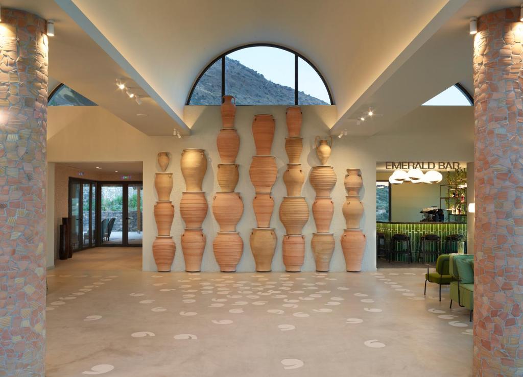 Mūsdienīgs interjers ar māla traukiem uz sienas, kas veido izteiksmīgu akcentu. Skats uz bāru un atpūtas zonu, papildināts ar elegantu apgaismojumu un augu dekorācijām.