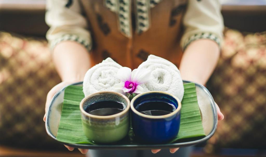 Pasniedziet tējas un mitras dvielīšu kombināciju, dekorētu ar orhideju uz lapu pamatnes. Ideāls brīdis relaksācijai un izbaudīšanai.