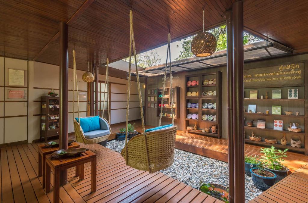 Mūsdienīgs interjers ar šūpuļtīkliem un koka grīdu, kurā ir grāmatu plaukti un dekoratīvi elementi. Telpa rada mierīgu un relaksējošu atmosfēru.