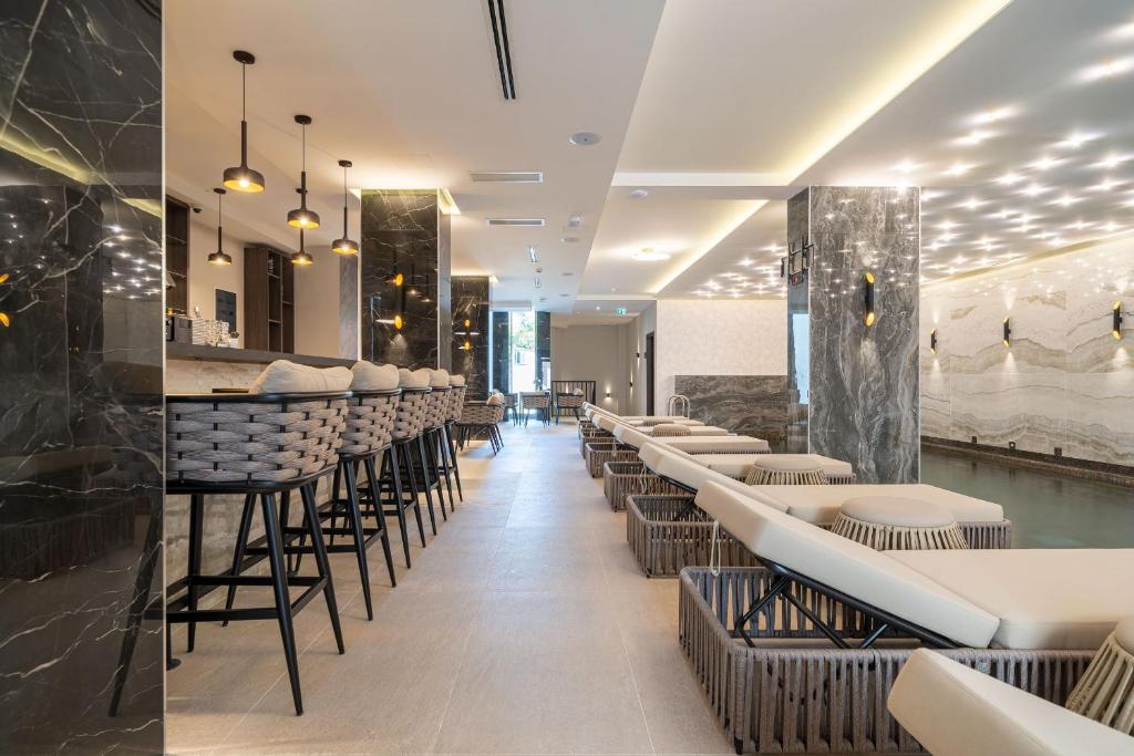 Mūsdienīga spa telpa ar elegantu dizainu, apgaismojumu un relaksējošu atmosfēru, kurā redzami stilīgi krēsli un bārs.