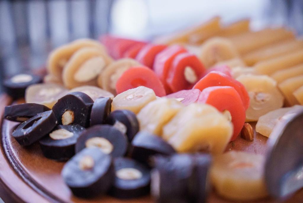 Krāsains siera un riekstu uzkodu šķīvis ar melnām, dzeltenām un sarkanām šķēlītēm, kas izkārtotas pievilcīgā veidā.