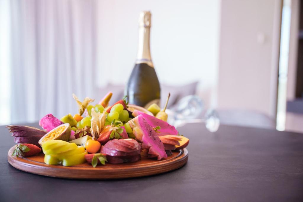 Krāsains augļu un dārzeņu šķīvis ar šampanieša pudeli fona. Ideāls, lai svinētu īpašus brīžus ar svaigām garšām.