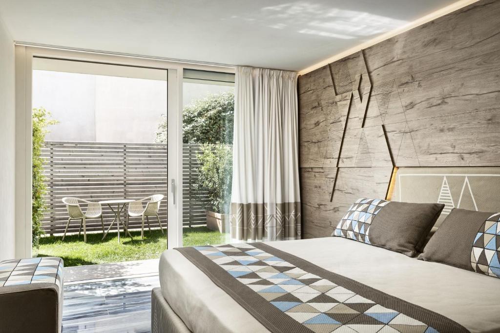 Mūsdienīgs guļamistabas interjers ar koka akcentiem un skatu uz dārzu. Istabā ir gaisīga atmosfēra ar mierīgu dekoru un komfortablu gultu.