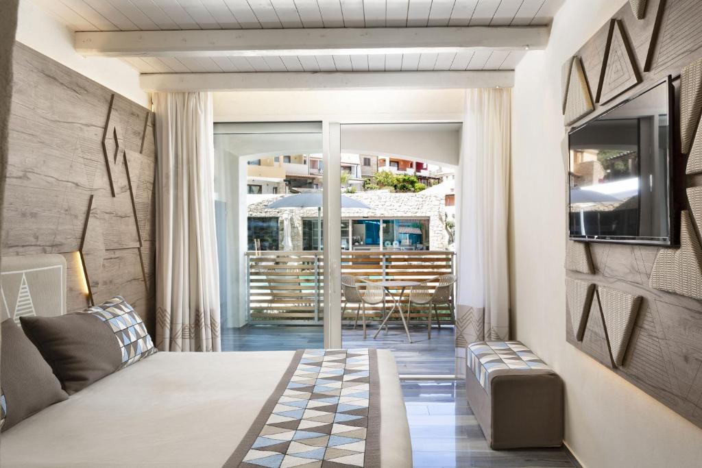 Moderns viesnīcas numurs ar elegantu interjeru, koka apdari un lieliem logiem, kas paver skatu uz terasi. Numurā ir gulta ar rakstainām spilveniem un televizors uz sienas.