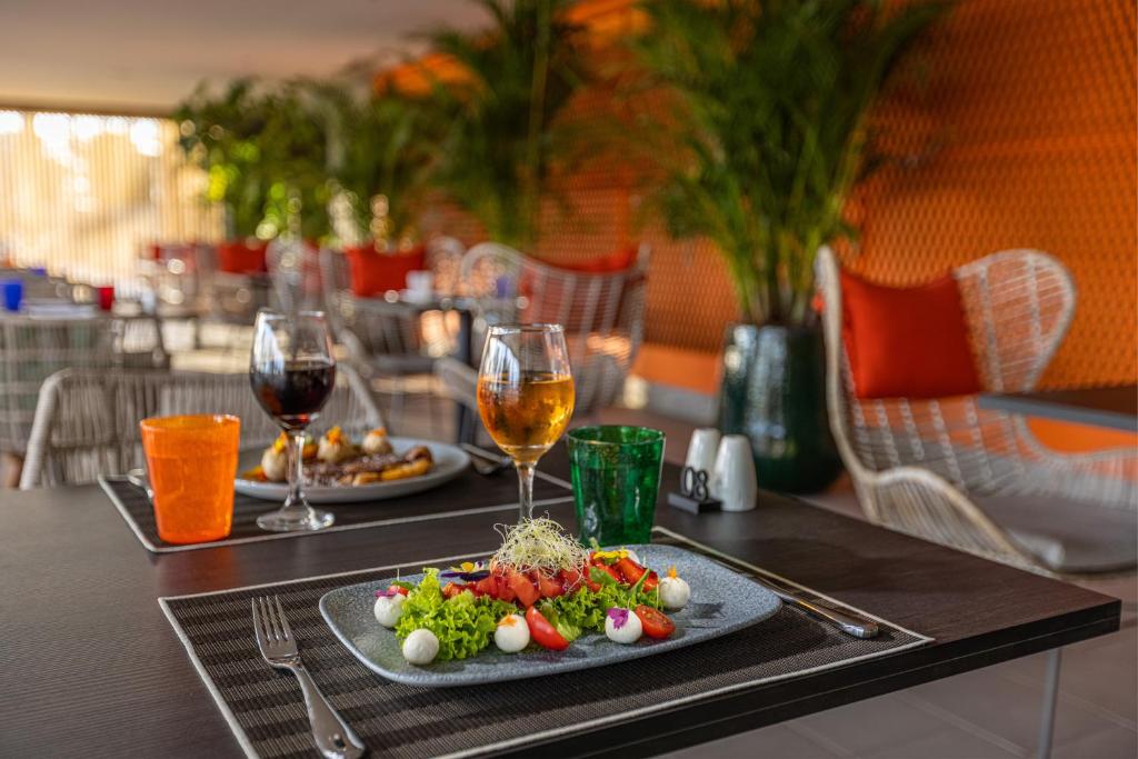 Svaiga salātu šķīvis ar tomātiem, mozzarella bumbiņām un zaļumiem, kopā ar dzērieniem, viesmīlīgā un modernā restorāna atmosfērā.