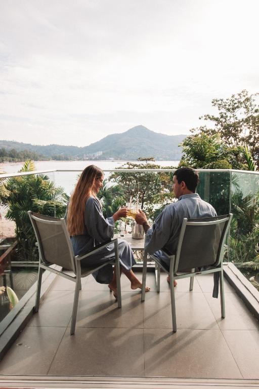 Pāris bauda dzērienus uz balkona ar skatu Novotel Phuket Kamala Beach.