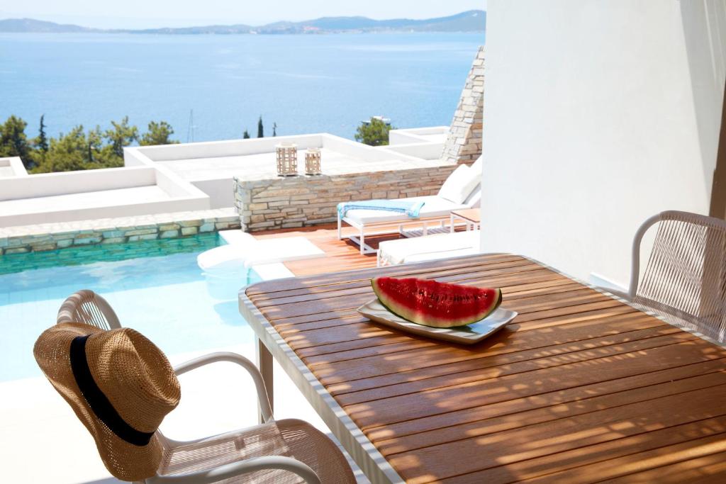 Vasaras brīvdienu atmosfēra ar ūdensmeloni uz koka galda, blakus peldbaseinam un skatu uz jūru. Ideāla vieta relaksācijai un atpūtai.