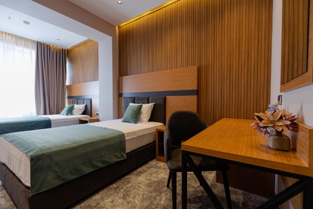 Mūsdienīgs viesnīcas numurs ar divām gultām, koka akcentiem un rakstāmgaldu. Interjers ir gaišs un elegants, radot komfortablu atmosfēru.