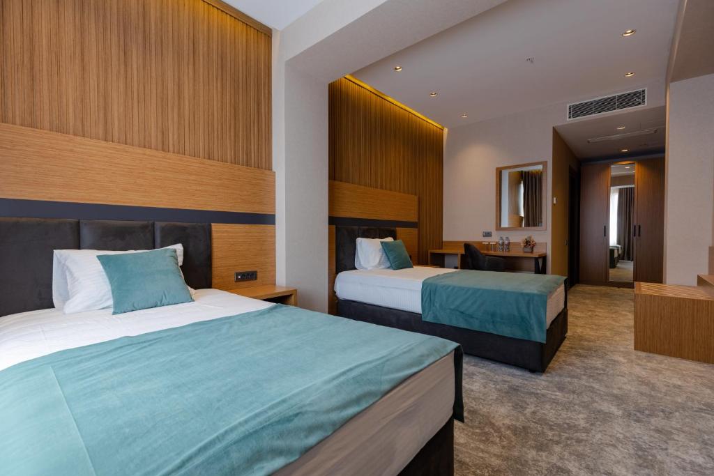 Mūsdienīga viesnīcas istaba ar divām gultām, koka apdari un maigiem toņiem. Istaba ir gaiša un ērta, ar rakstāmgaldu un spoguli.