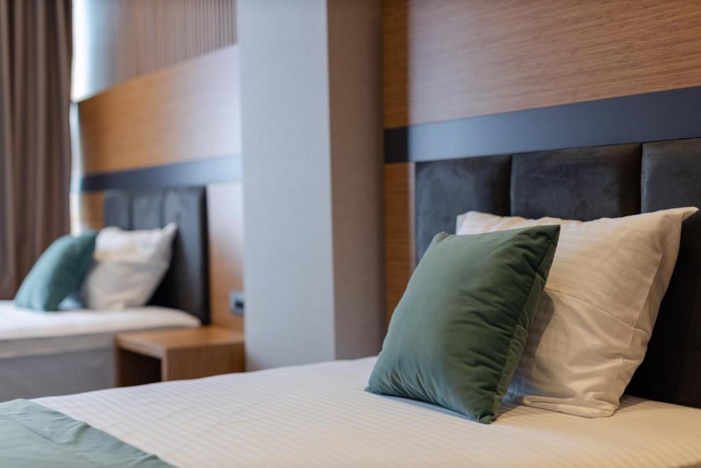 Mūsdienīgs viesnīcas numurs ar ērtām gultām un dekoratīvām spilveniem, radot relaksējošu atmosfēru.