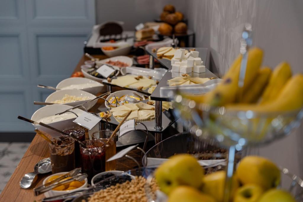 Bagātīgs brokastu bufete ar dažādiem sieriem, augļiem, ievārījumiem un graudaugiem, kas iekārtota elegantā vidē. Ideāla izvēle gardēžiem.