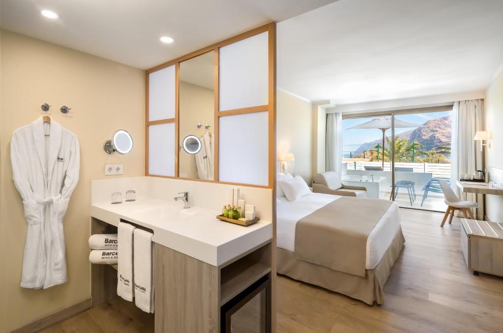 Mūsdienīga viesnīcas istaba ar koka grīdu, vannas istabu un balkonu ar skatu uz kalniem. Istabā ir gultas, sēdvietas un ērtības, piemēram, tējkanna un izlietne.