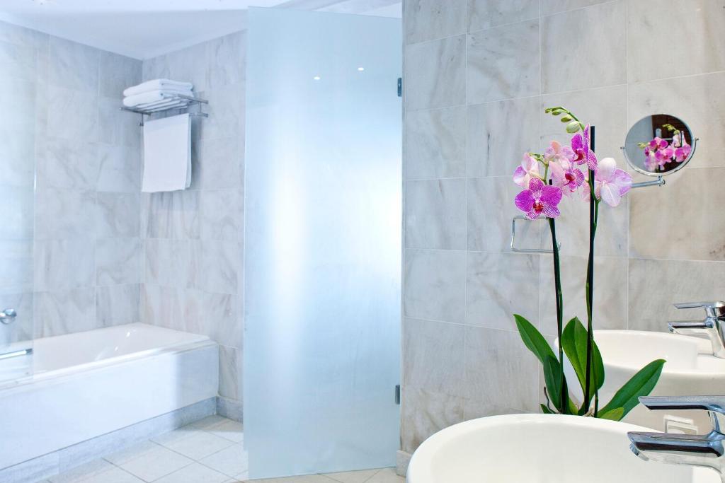 Mūsdienīgs vannas istabas interjers ar skaistām orhidejām un elegantu dušas kabīni. Gaišas krāsas flīzes un moderni santehnikas elementi rada relaksējošu atmosfēru.