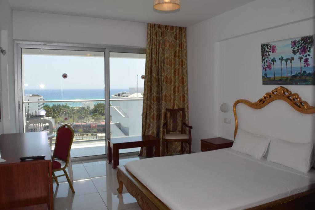 Gaiša viesnīcas istaba ar skatu uz jūru, iekārtota ar ērtu gultu un koka mēbelēm. Logi piedāvā lielisku skatu uz apkārtni un jūru.