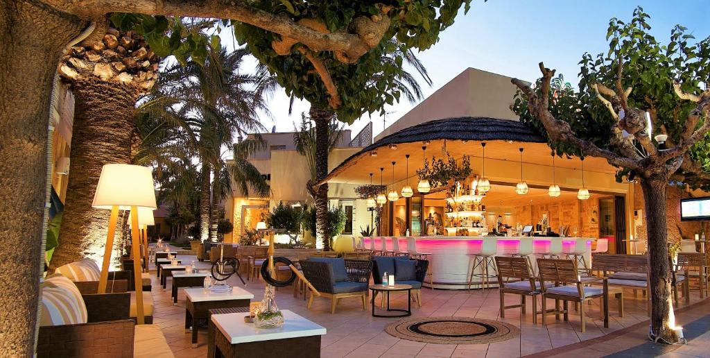 Elegants āra bārs ar modernu dizainu, iekārtots ar palmām un ērtām mēbelēm, kurā ir apgaismojums un dzīvīga atmosfēra. Ideāla vieta relaksācijai un izklaidei.