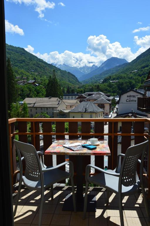 Balkons ar divām krēsliem un galdu, no kura paveras skats uz kalniem un zaļām ielejām, ar mākoņiem debesīs. Ideāla vieta relaksācijai un ainavas baudīšanai.