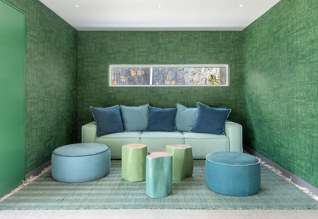 Mūsdienīgs dzīvojamā istaba ar zaļiem toņiem, ieskaitot dīvānu un krēslus, kas apvienoti ar dabīgu akmens elementu. Interjeru papildina mīkstās mēbeles un paklājs, radot relaksējošu atmosfēru.