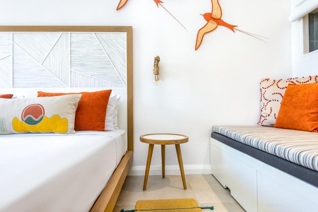 Moderns guļamistabas interjers ar spilgtiem akcentiem, ērtiem spilveniem un stilīgu galdu. Sienā ir dekoratīvi putni un ģeometriski elementi.