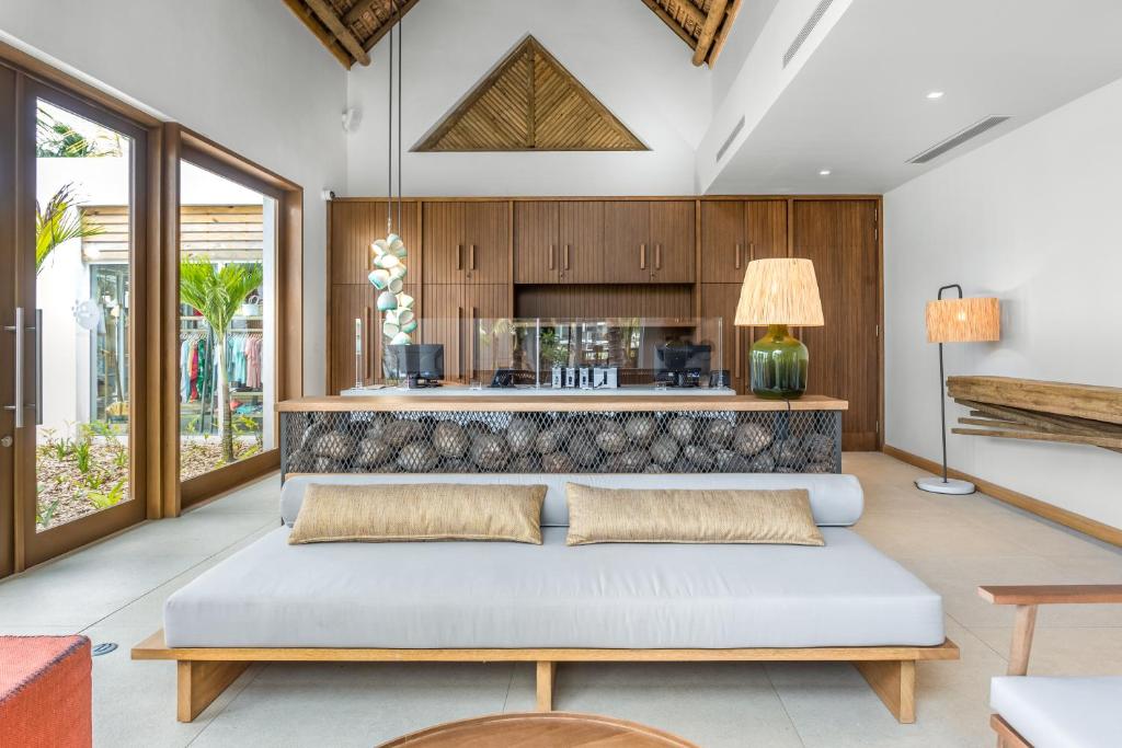 Mūsdienīga viesistaba ar atvērtu plānojumu, kas ietver koka mēbeles, gaišus toņus un lielus logus, kas nodrošina dabīgu apgaismojumu un skatu uz dārzu.