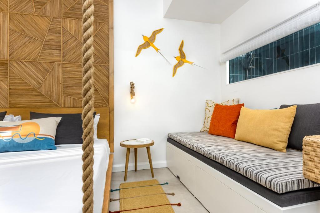 Mūsdienīgs guļamistabas interjers ar koka sienu, virs kuras ir dzeltenas putnu dekorācijas. Gultas galvgalis veidots no rotājošiem koka elementiem, un telpā ir ērta dīvāna zona ar spilveniem.