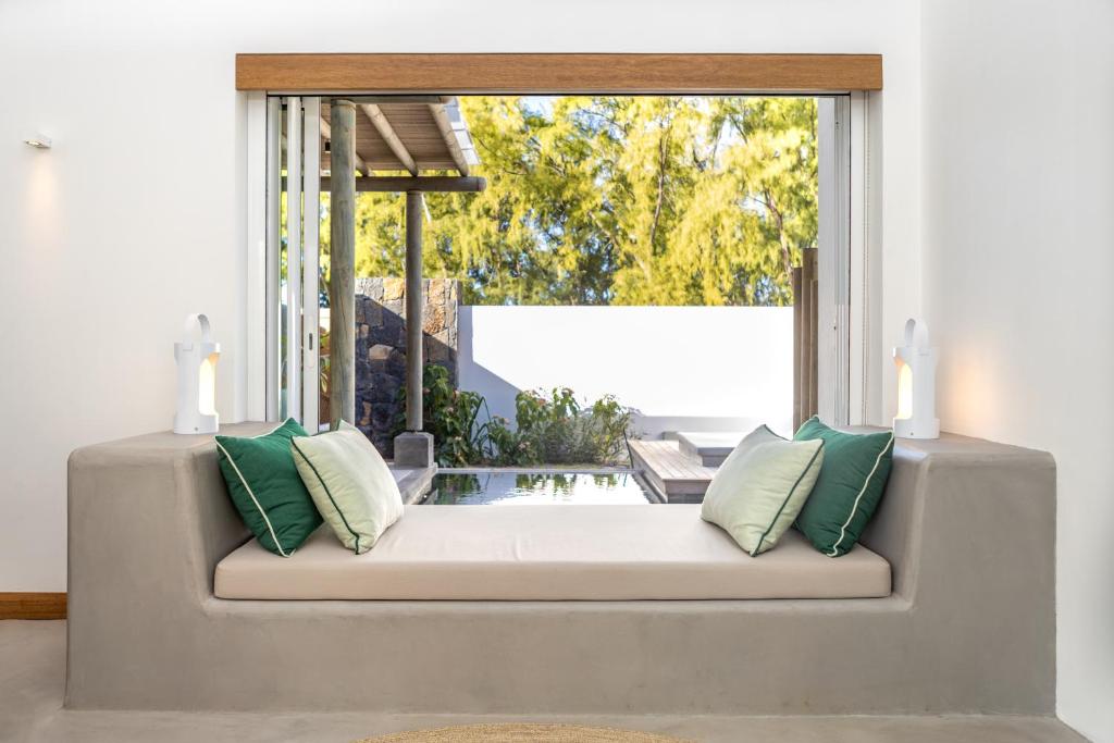 Gaismas un mūsdienīga interjera dizaina telpa ar ērtiem spilveniem un skatu uz dārzu. Lielie logi ļauj ieplūst dabiskai gaismai un rada patīkamu atmosfēru.