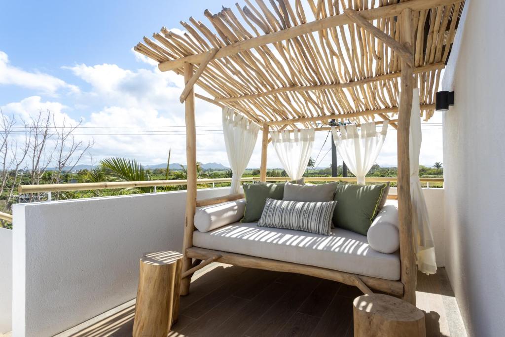 Mūsdienīgs koka dīvāns ar baltiem spilveniem un zaļām detaļām, izvietots uz balkona ar skatu uz dabu. Ideāla vieta relaksācijai un atpūtai.