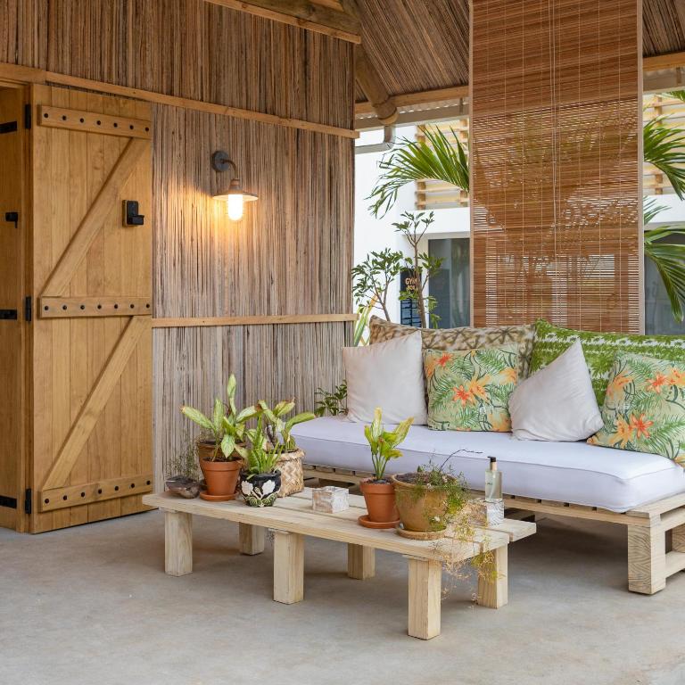 Mūsdienīgs un ērts atpūtas stūris ar koka mēbelēm, dīvānu ar pušķotiem spilveniem un augiem, radot relaksējošu atmosfēru.