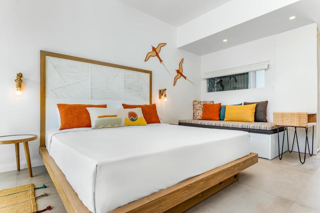 Mūsdienīgs guļamistabas interjers ar lielu gultu, spilveniem un stilīgu sēžamo stūrīti, akcentēts ar krāsainiem spilveniem un dekoratīvām sienas gleznām. Gaismas un telpas dizains rada patīkamu atmosfēru.