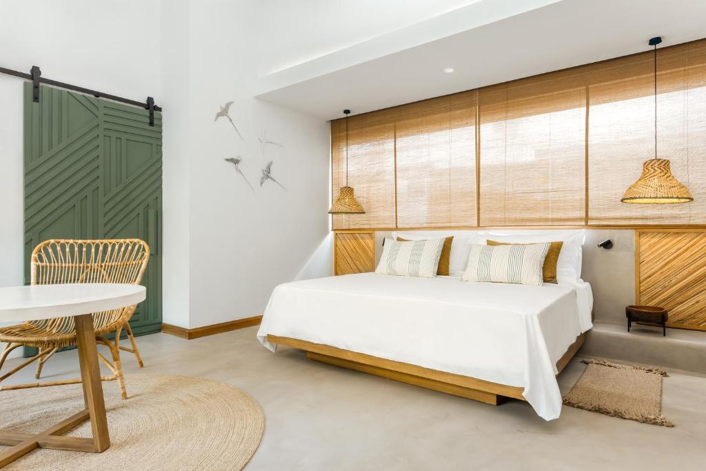 Mūsdienīga guļamistaba ar baltu gultu, dabīgā koka akcentiem un rakstainām spilveniem, apgaismota ar rotājumu lampām un dekoratīvām sienas detaļām. Stilīgs interjers ar zaļām durvīm un ērtu galdu.