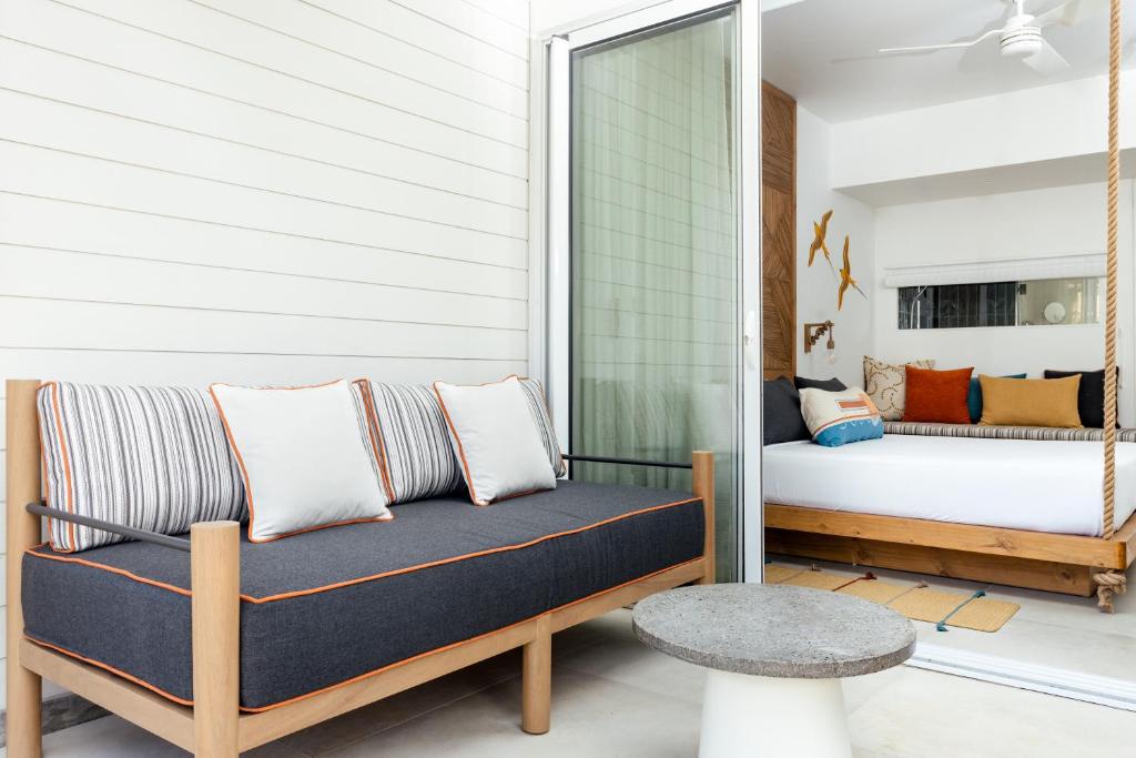 Mūsdienīga viesnīcas istaba ar elegantu dīvānu un nelielu galdu, kas piedāvā atpūtu un komfortu. Interjerā redzami krāsaini spilveni un gaišas krāsas sienas.