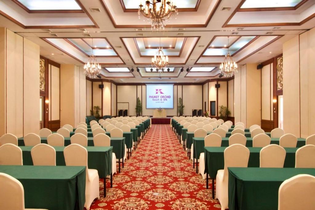 Konferenču zāle ar zaļiem galdiem un baltām krēslām, sagatavota pasākumam. Fona ekrānā redzams viesnīcas "Phuket Orchid Resort & Spa" logo.