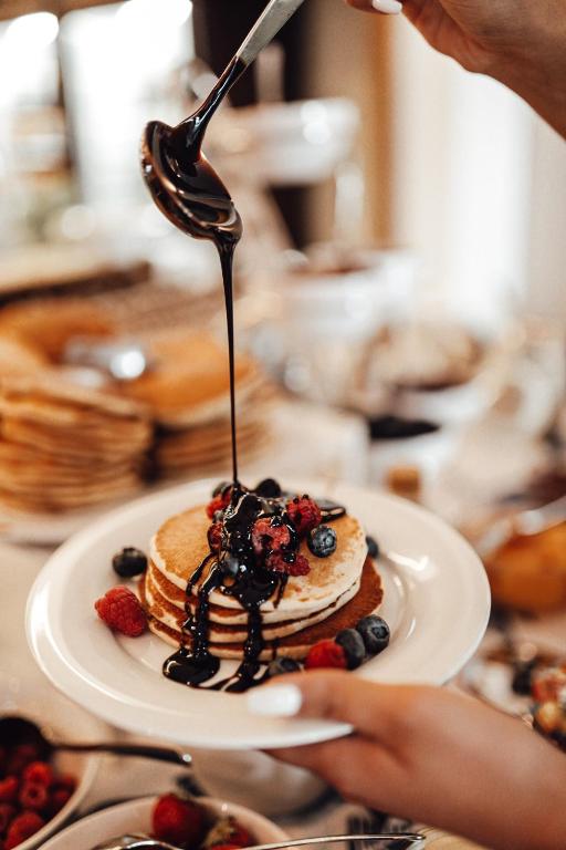 Pankūkas ar šokolādes mērci un ogām, pasniegtas uz baltas šķīvja.