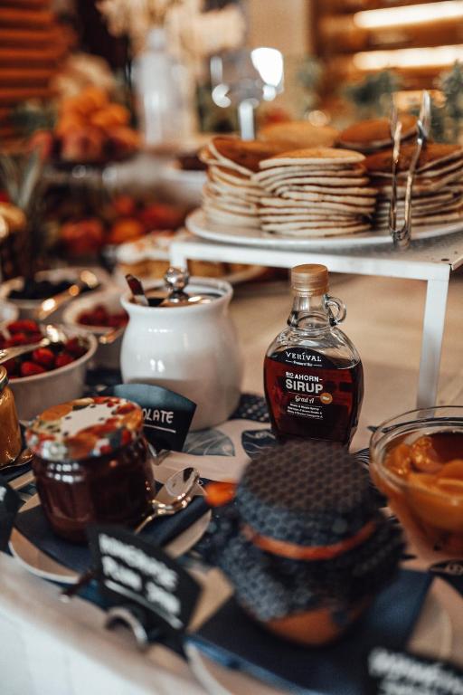 Bagātīgs brokastu galds ar pankūkām, sīrupu un dažādiem ievārījumiem, ko rotā svaigi augļi un rieksti. Ideāla izvēle, lai uzsāktu dienu ar gardu maltīti.