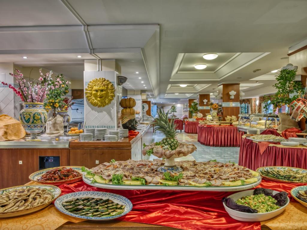 Bufete ar dažādiem ēdieniem un dekorācijām, tostarp ziediem un augļiem, radot viesmīlīgu atmosfēru. Ideāli piemērots svinībām vai īpašiem pasākumiem.