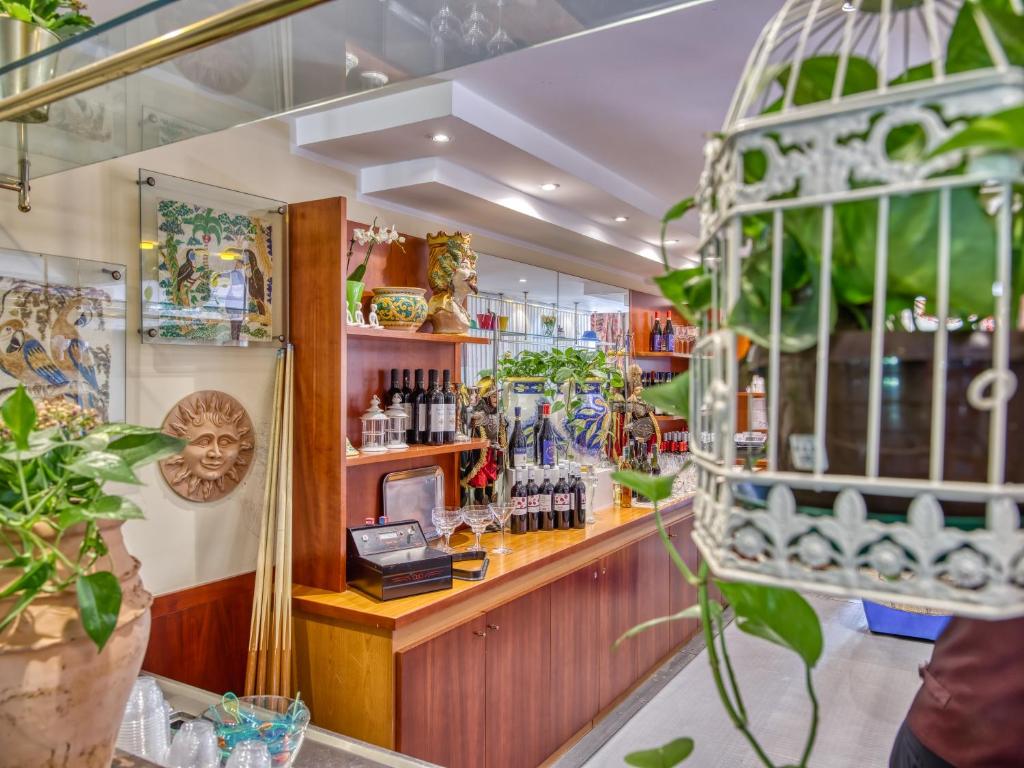 Interjers ar bāru, kurā ir vīna pudeļu kolekcija, dekoratīvi elementi un zaļās augu kompozīcijas, radot patīkamu atmosfēru.