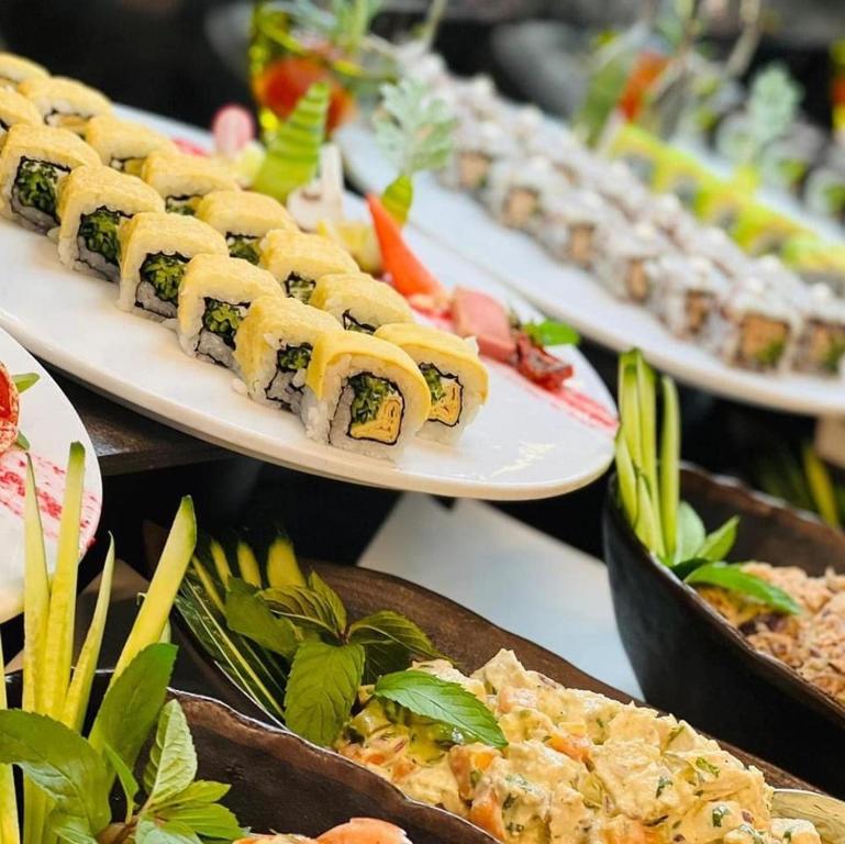 Svaigu sushi un gardu salātu izvēle uz galda, kas rotāts ar zaļumiem. Ideāls ēdiens svinībām vai īpašiem pasākumiem.