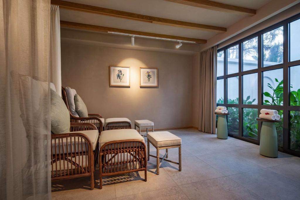 Mūsdienīga relaksācijas telpa ar ērtiem krēsliem, gaismas apgaismojumu un lieliem logiem, kas ļauj ieplūst dabiskai gaismai. Telpas interjerā ir redzami eleganti mākslas darbi un zaļumi, kas rada mierīgu atmosfēru.