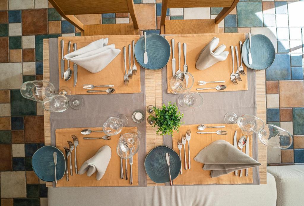 Galda uzstādījums ar eleganti salocītām salvetēm, modernām šķīvju un galda piederumu kombinācijām, radot viesmīlīgu atmosfēru. Interjers papildināts ar krāsainu grīdas flīžu dizainu.