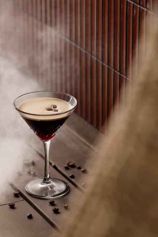 Elegants martini kokteilis ar kafijas putām un grauzdētām kafijas pupiņām, radot noslēpumainu atmosfēru. Dūmi piešķir dzērienam unikālu šarmu.