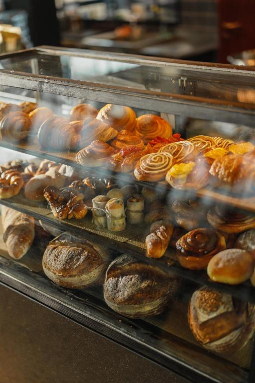 Pārtikas vitrīna, kas pilna ar dažādiem konditorejas izstrādājumiem, tostarp maizēm un saldumiem.