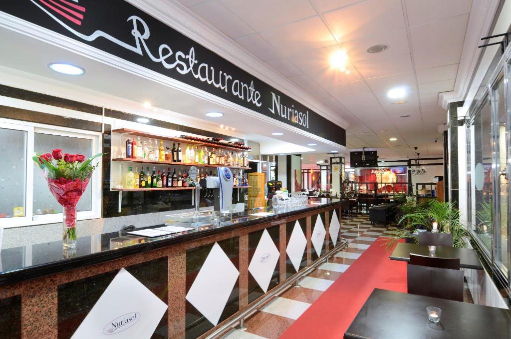 Restorāna Nuriasol bārs ar dzērienu plauktiem un ziedu kompozīciju. Mūsdienīga iekārtojuma telpa ar siltu atmosfēru.